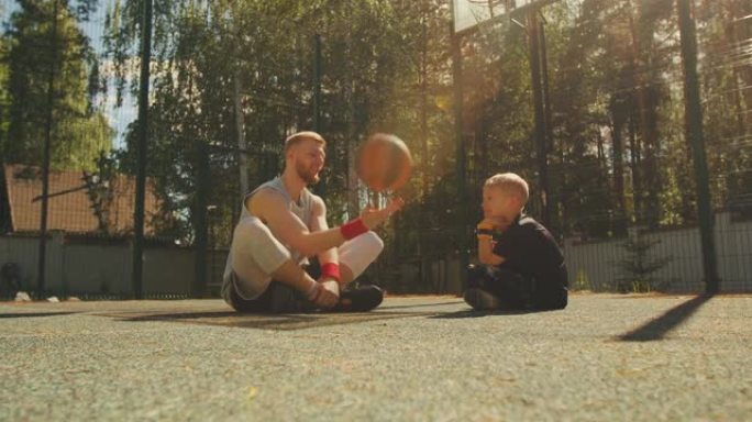男子篮球运动员教练训练男孩在阳光下在篮球场上用手指旋转球