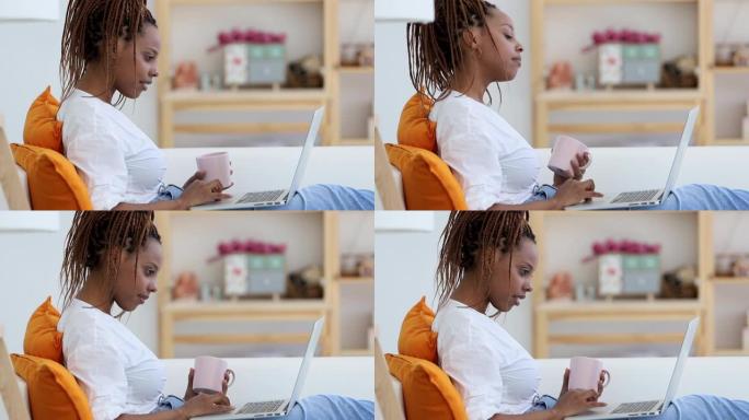 侧视女人在家滚动笔记本电脑Spbi上的新闻提要。黑人美国千禧一代女性