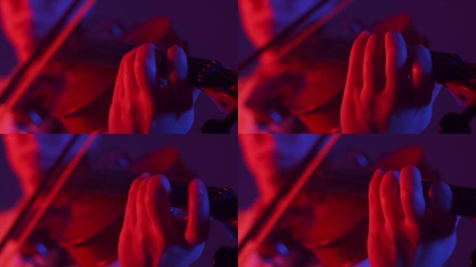 女小提琴手用弓拉小提琴。音乐家女用手指和弓拉小提琴，红蓝光亮，特写