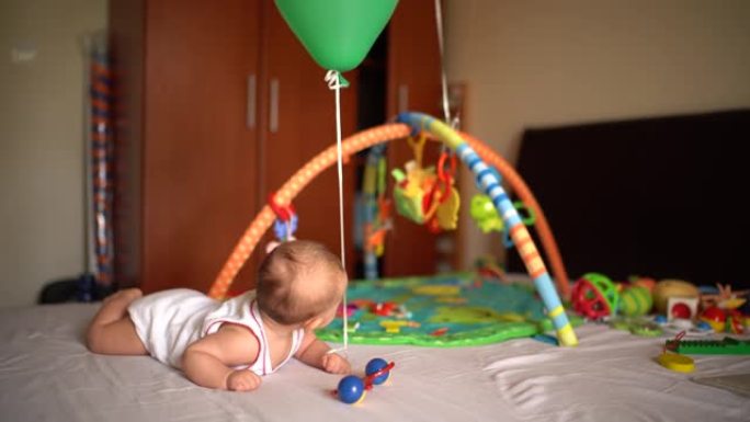 手上绑着气球的婴儿躺在肚子上的床上