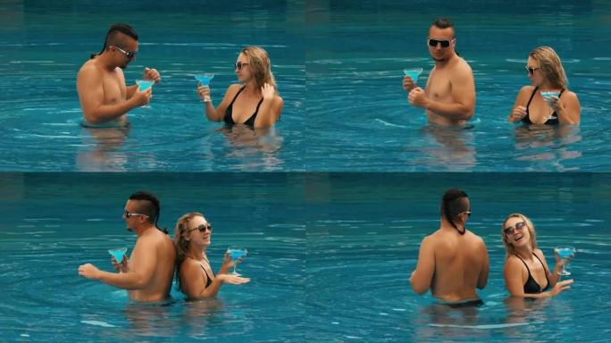 这对相爱的情侣在酒店室外的游泳池里拥抱亲吻，喝着蓝色的鸡尾酒。白种人男人和女人的肖像。