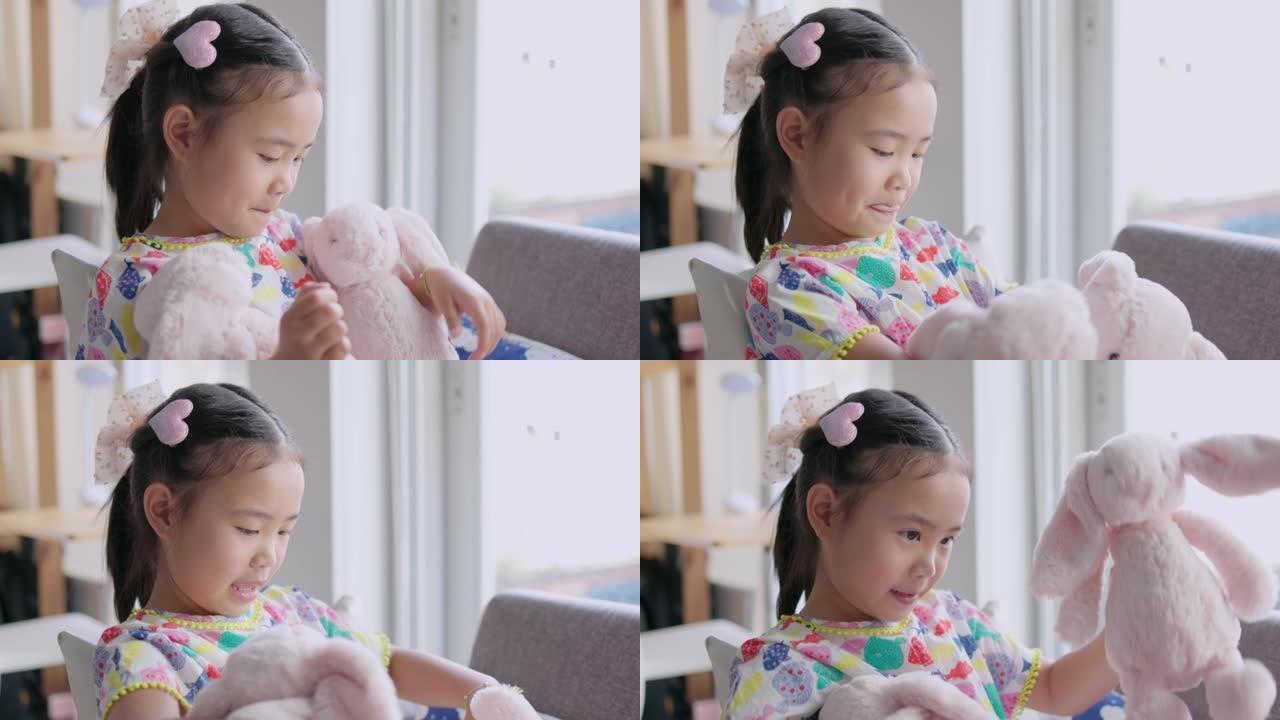 玩粉色兔子娃娃的亚洲女孩。