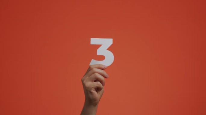 手显示第三。带有数字的手臂，由雕刻纸制成的第三个数字，用于博客，投票或学习