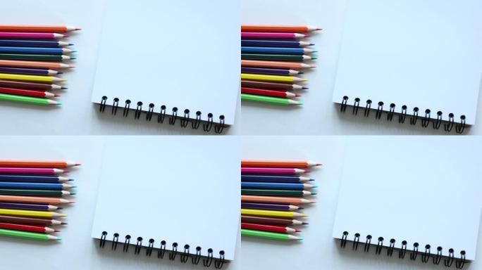 彩色铅笔躺在白色的桌子上，旁边有螺旋记事本。回到学校教育学习理念