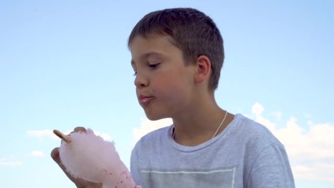 这个男孩正在海边吃棉花糖。粉色棉花糖。