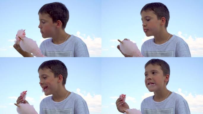 这个男孩正在海边吃棉花糖。粉色棉花糖。