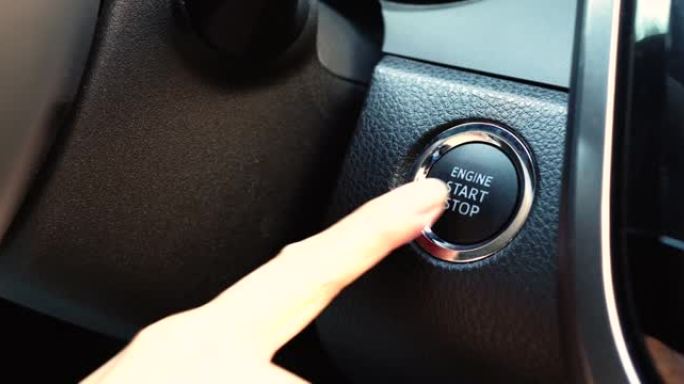 一个女人按下汽车启动按钮启动汽车发动机的特写
