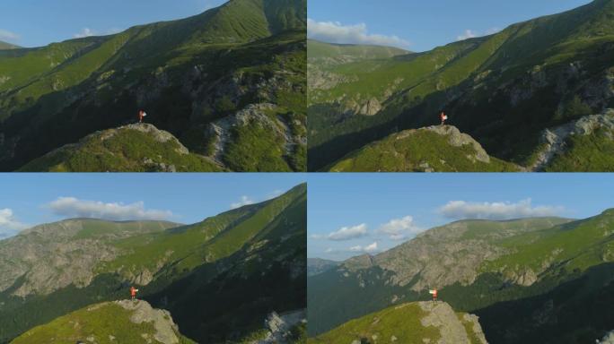 无人驾驶飞机视图孤独的徒步旅行者拿着地图，坐在山顶的岩石边缘