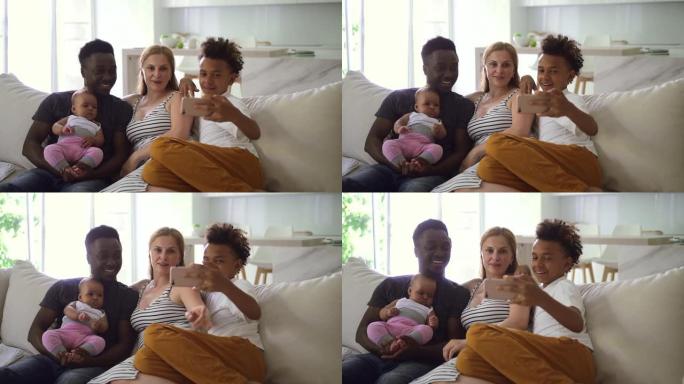 四口之家坐在现代客厅Spbd的沙发上通过智能手机进行视频通话