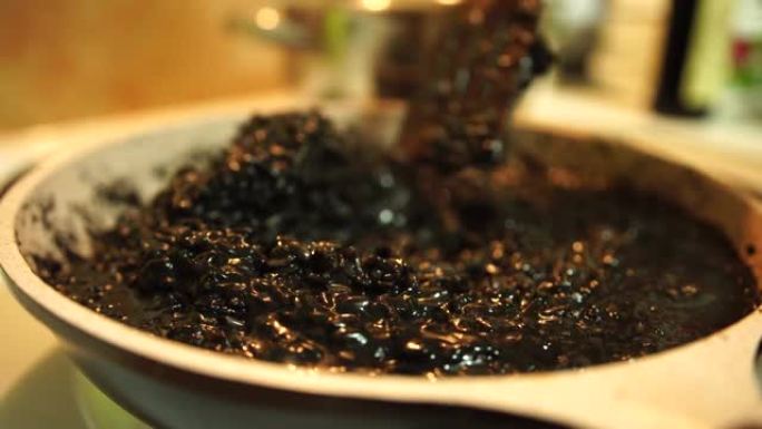 用锅铲在锅里搅拌黑色意大利调味饭。煮米饭做黑烩饭。