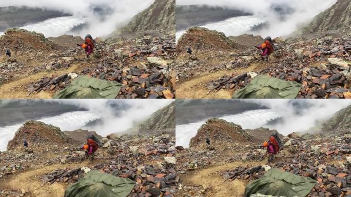 一位精疲力竭的游客背着大背包，沿着山间小路跌跌撞撞地走过石头和巨石