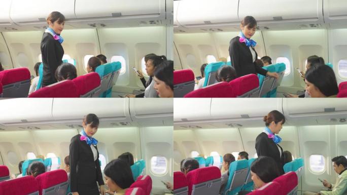 美丽的亚洲空姐或空姐走在过道上，关闭行李舱，并在起飞前检查飞机乘客。飞机上机组人员的安全检查程序。
