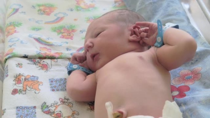 一个手上戴着妇产医院手镯的新生儿躺在婴儿床上