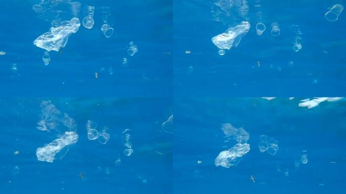 许多塑料垃圾被阳光照射下的地表水反射的水漂浮。水下射击，海洋的塑料污染。红海的大规模塑料污染 (4K