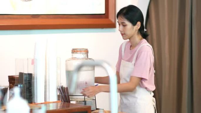 4k年轻亚洲女服务员开门前打扫咖啡店。