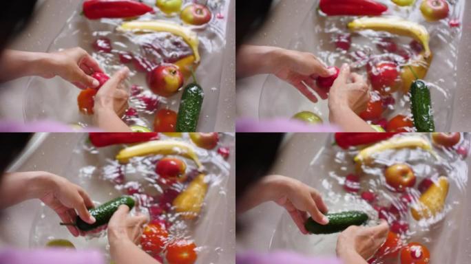 女性手洗黄瓜辣椒番茄香蕉梨苹果柠檬。手洗新鲜蔬菜水果用水在盆中慢动作。素食。新鲜收获。洗水果和蔬菜。