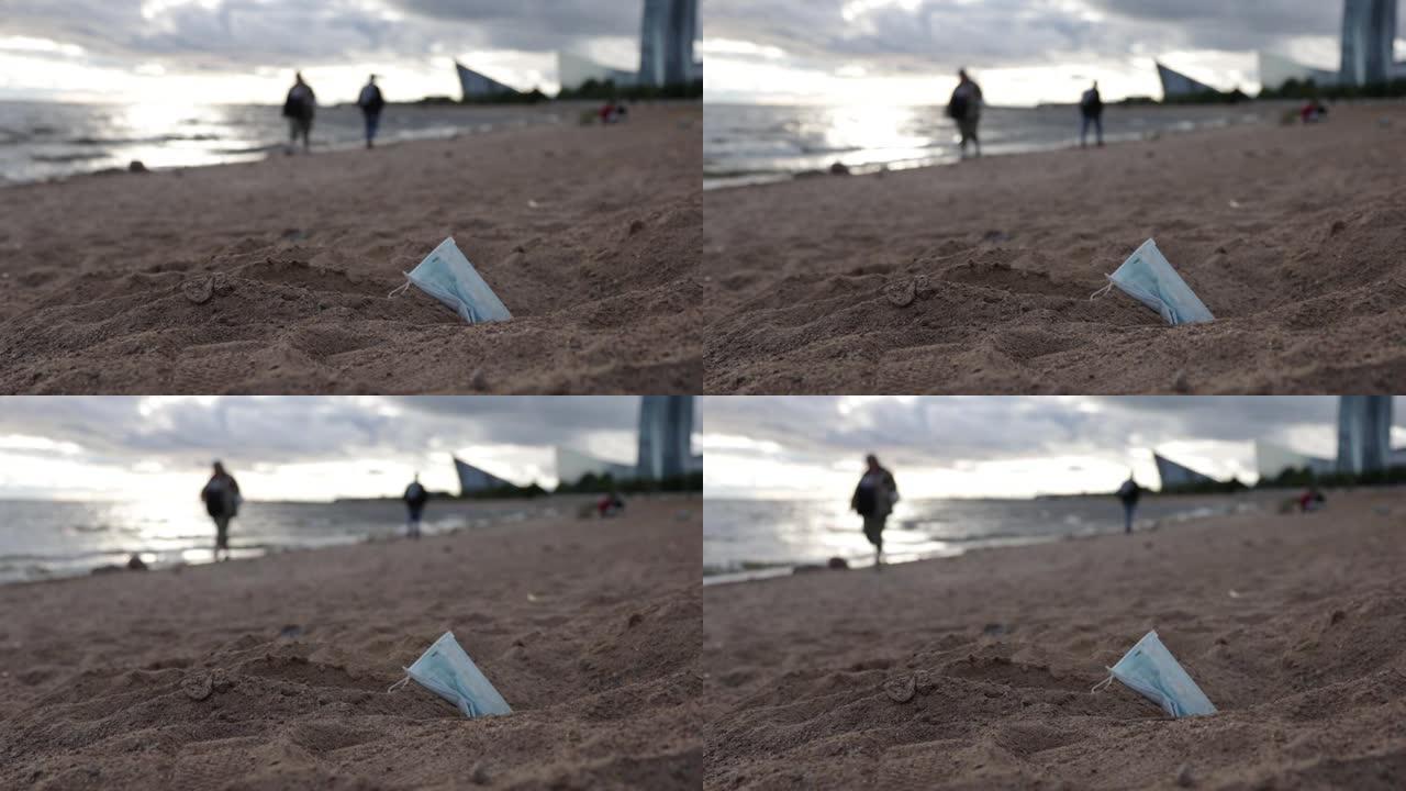 海滩上的垃圾，人们在肮脏的海滩上在海边散步。人们走过垃圾