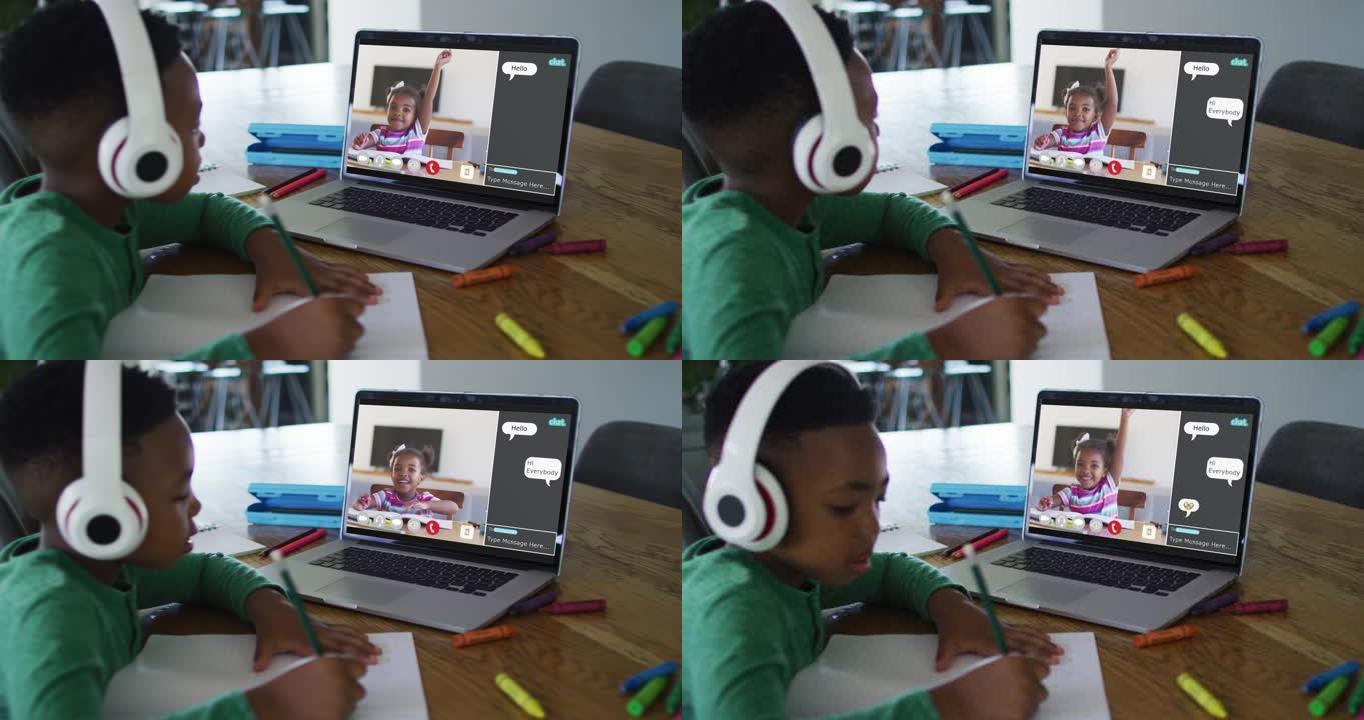 非裔美国男孩戴着耳机在家里用笔记本电脑进行视频通话时做作业