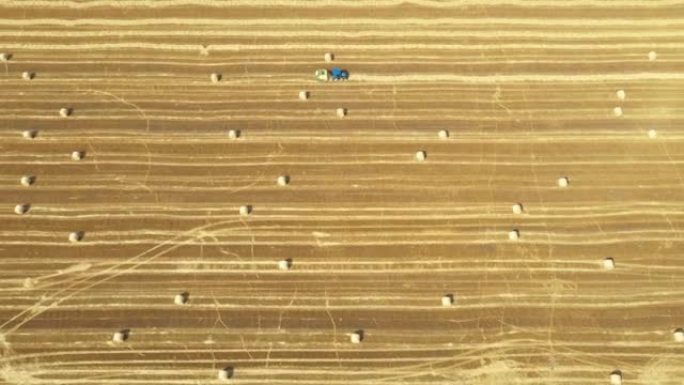 拖拉机拖捆机的鸟瞰图从收获的土地收集稻草