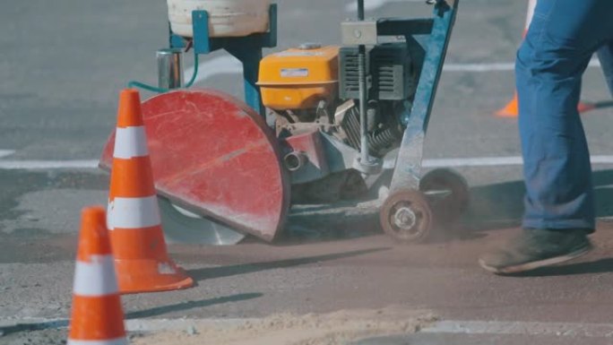 道路工程。道路用地板锯工作。工人用地锯锯沥青