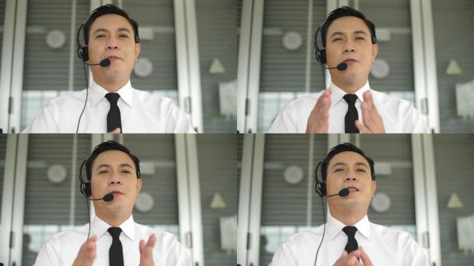 戴着耳机和支持客户，看着相机工作的亚洲男性呼叫中心的肖像照片