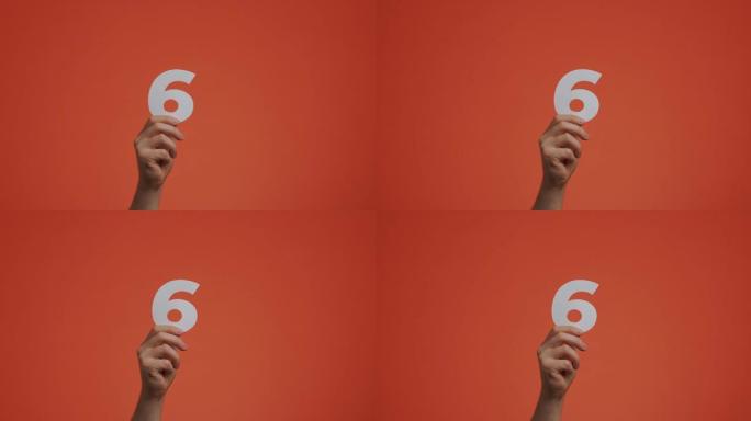 手显示第六号。带有数字的手臂，第六个数字由雕刻纸制成，用于博客，投票或学习