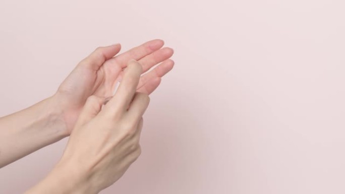 浅粉色背景上使用洗手液喷雾分配器的女性手-停止运动动画