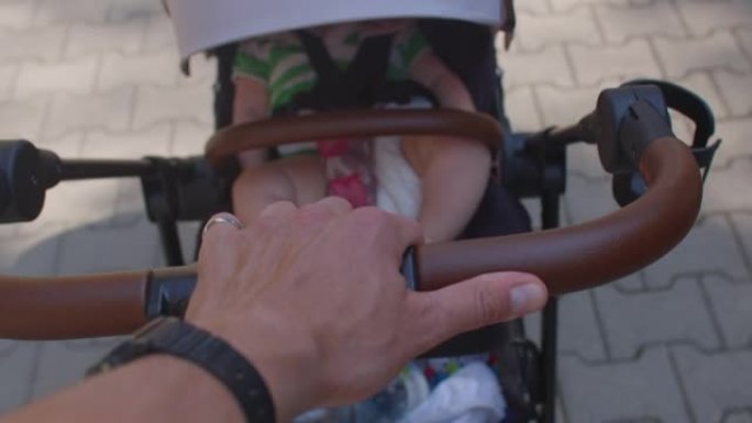 Hand带着一个孩子的婴儿车穿过人行道。育儿假。