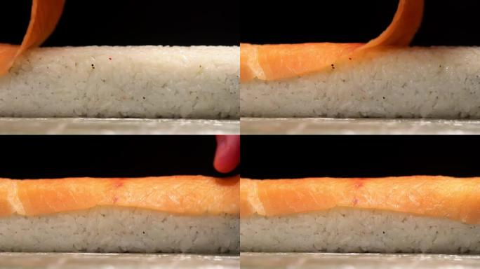 sushiman的手在滚动，宏观，侧视图上布置鲑鱼片。卷材的特写准备。日本料理概念