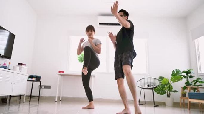 年轻的亚洲健身夫妇在客厅拳击武术
