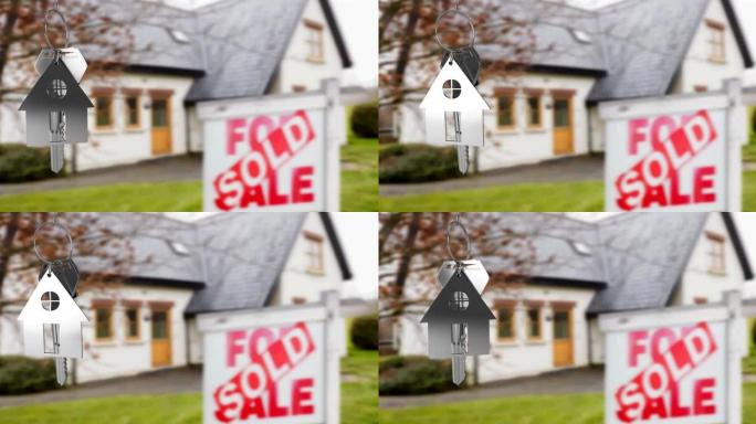 银色房子钥匙扣和钥匙的动画，悬挂在带出售标志的模糊房子前面