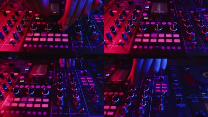 专业DJ在霓虹灯的数字音乐控制台上调整推子，特写镜头。概念现代俱乐部音乐