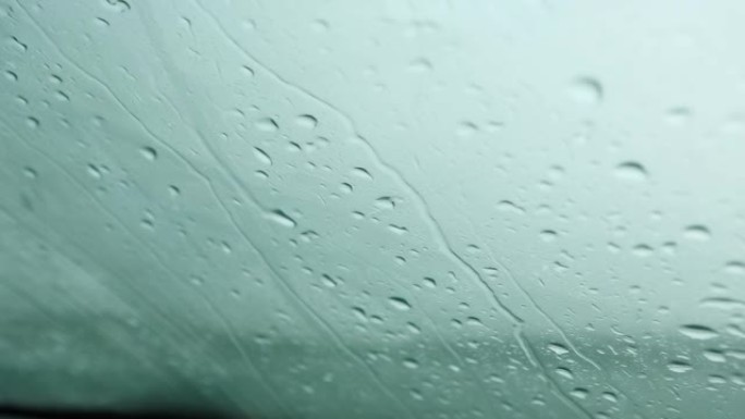 雨滴从汽车挡风玻璃上跑下来。恶劣的天气条件，秋天，能见度有限的条件。寒冷，潮湿，悲伤
