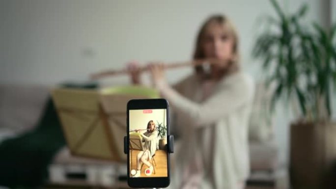 女人演奏长笛，管乐器并通过电话录制视频以用于社交媒体。独奏音乐家电影