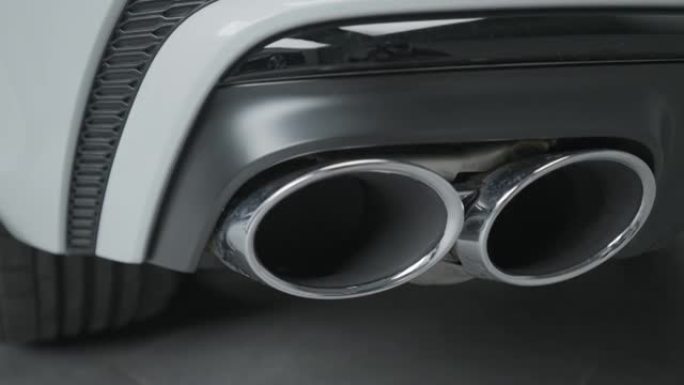 新车排气管特写。行动。豪华设计的新车型上的双排气管。带排气管的新汽车零件