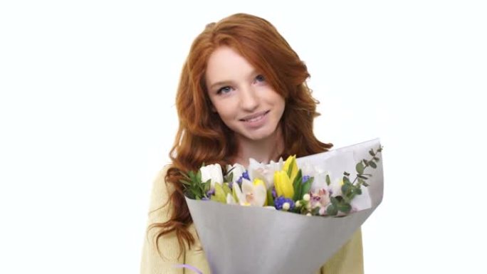 长卷发红头发的幸福女人闻到白色背景上的花朵