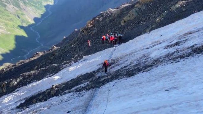 登山者沿着冰道穿过冰碛，用皮带抓住绳索