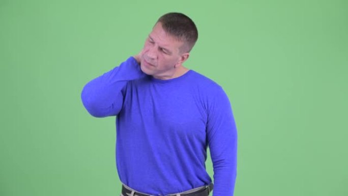 工作室拍摄的男子在绿色背景下脖子痛