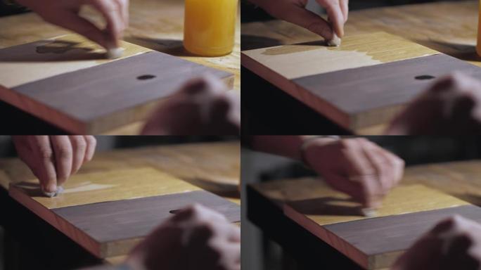 用海绵在木橡木板上涂油。木材浸渍的应用。木工概念。木材污渍