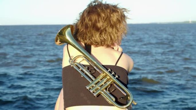 一个女人坐在海上等待奇迹，在乐器后面