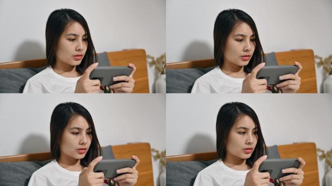 严肃的年轻亚洲女子在睡前用手机在线玩游戏
