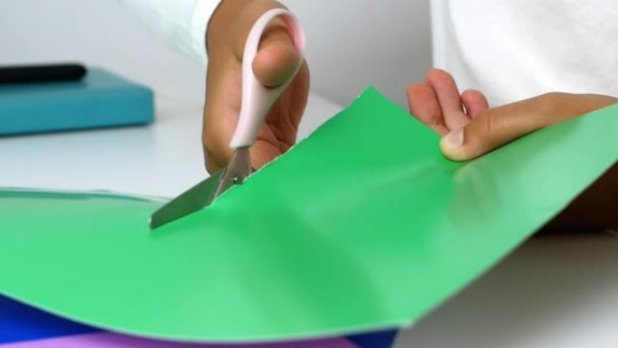 一个小女孩用自己的手雕刻假货，用剪刀从彩纸上剪下来。特写4k视频。