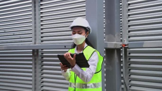 工程师正在检查工业冷却塔空调是大型工业建筑的水冷却塔空气冷水机组，以控制空气系统，戴着口罩以保护污染