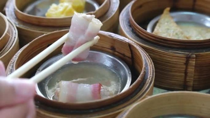 用筷子在餐厅用竹篮里用手吃传统的中国食物新鲜美味可口的蒸肉点心