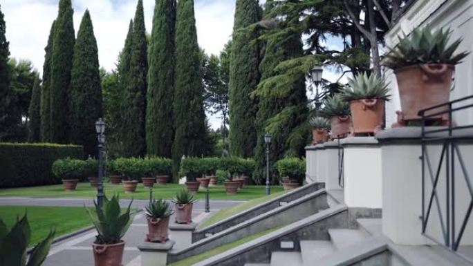 历史悠久的住宅物业，带有私人花园庭院，白色的古老宫殿，天空背景上环绕着雄伟的常绿柏树。巨大的砖棕色花