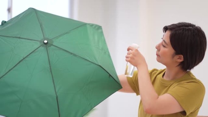 一名妇女在折叠伞上喷洒防水喷雾