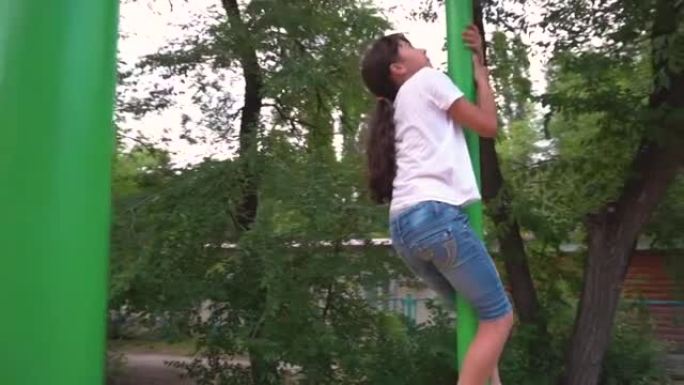 一个女孩爬上绿色的单杠