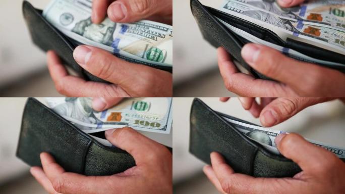 汉德把一张百元美钞放进一个黑色的皮夹里，拿了一张钞票。现金，一堆百元大钞特写。金融、经济、理财、经济