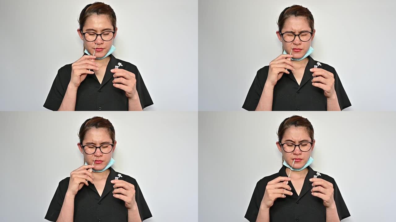年轻的亚洲妇女使用鼻拭子快速抗原测试试剂盒，从鼻咽中提取细胞样本。