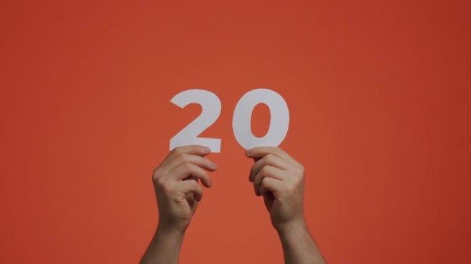 手中的20号。显示数字的人，20个由雕刻纸制成的数字，用于投票或数学学习